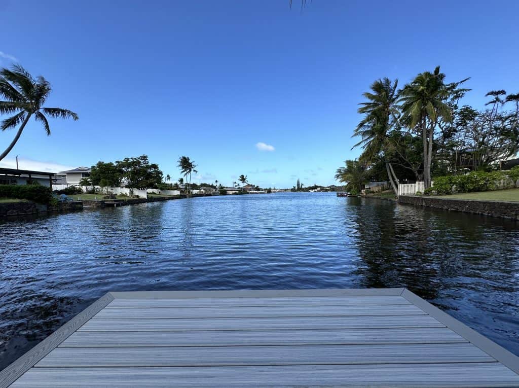 Lower level deck in Kailua, constructed with Trex Foggy Wharf deck boards and Pebble Gray border, offering a picturesque view of the tranquil lake and surrounding lush greenery. This custom deck provides a seamless connection to nature and water.