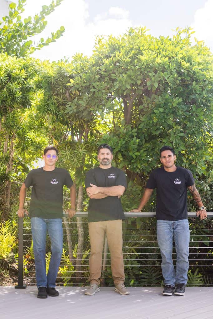 Noah, Chad, and Tama of Hawaii Deck Builders, a division of Hilweh Builders, standing on a TimberTech PVC deck with a Feeney stainless steel cable railing system, showcasing expert craftsmanship in deck construction.