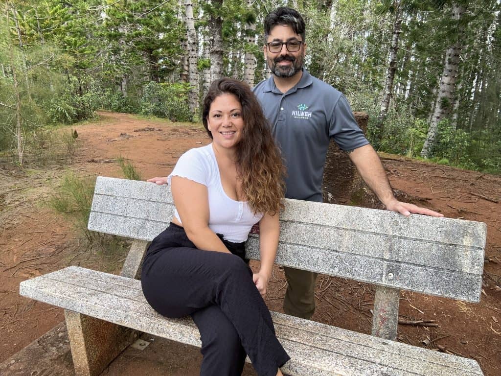 Liana and Chad Hilweh sitting at a bench in a park in Oahu.