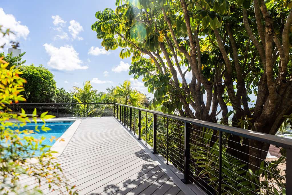 Side profile showing the Azek TimberTech PVC deck boards in Vintage Coastline, Feeney stainless steel cable railing, and beautiful greenery surrounding the Honolulu home.