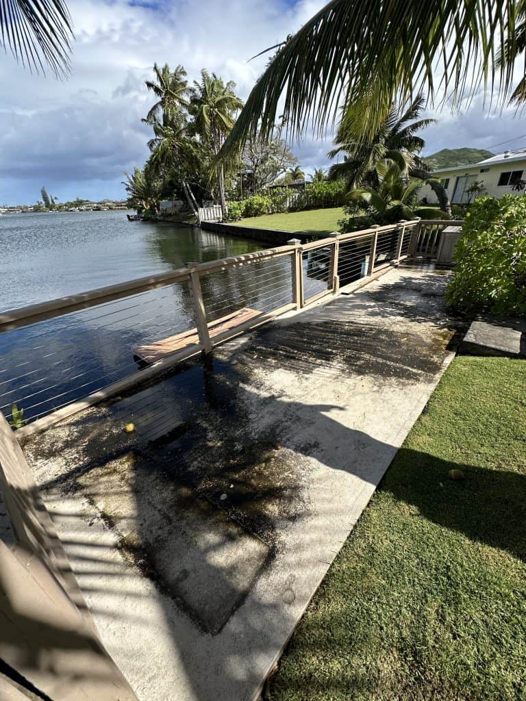 Wide-angle before photo of an old waterfront dock in Kailua, Oahu showing severe wood rot, weathered boards, and coastal damage — reviewed by Hawaii Deck Builders, certified deck safety specialists.